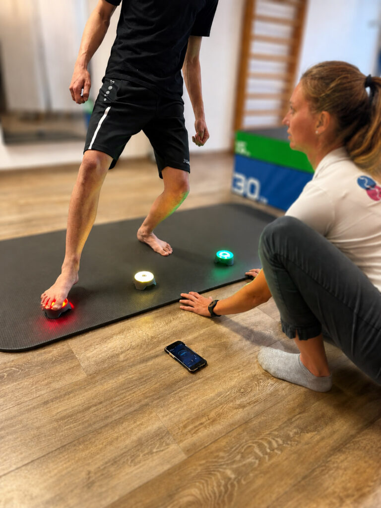 Physiotherapeutin und Patient beim spezifischen Schnelligkeits- und Aagilitytraining mit Reaktionslichtern